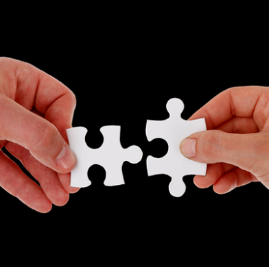 dwie dłonie trzymające dwa pasujące do siebie puzzle